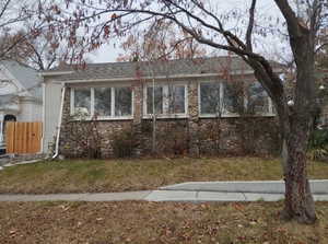 View of front of house featuring stone siding and a chimney