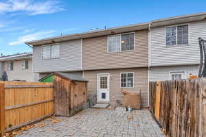 Rear view of house with a fenced backyard and a patio