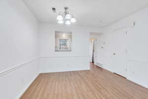 Unfurnished room with a chandelier and light wood-style flooring