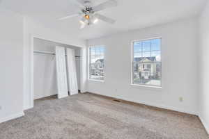 Unfurnished bedroom with carpet floors, ceiling fan, and multiple closets