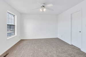 Carpeted spare room featuring ceiling fan and baseboards