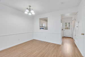 Unfurnished room with a chandelier, light wood finished floors, and a smoke detector