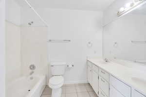 Bathroom with double vanity, bathtub / shower combination, and light tile patterned floors