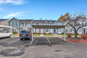 View of property featuring covered and uncovered parking