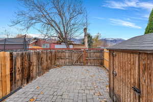 Fenced backyard featuring a mountain view, a gate, and a patio