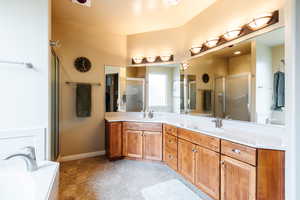 Bathroom featuring a garden tub, double vanity, and a stall shower