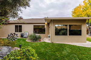 Back of house with a patio area, a lawn, stucco siding, and a tile roof