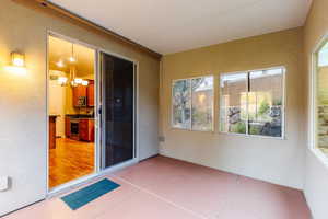 Unfurnished sunroom with plenty of natural light, a textured wall, a chandelier, and tile patterned flooring
