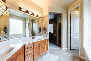 Bathroom featuring double vanity, a bath, and light flooring