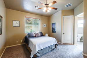 Bedroom featuring a ceiling fan, carpet floors, and ensuite bathroom