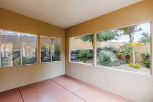 Unfurnished sunroom featuring a textured wall, plenty of natural light, and tile patterned floors