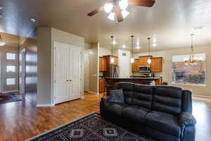 Living area with a chandelier, light wood-style flooring, and ceiling fan
