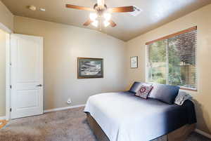 Carpeted bedroom with lofted ceiling and ceiling fan
