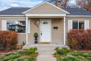 Property entrance featuring a shingled roof and a chimney
