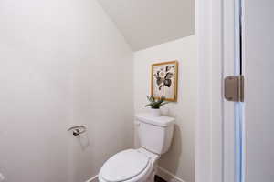 Bathroom featuring toilet and lofted ceiling