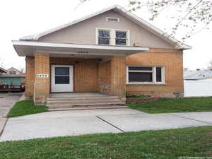View of front facade with brick siding, covered porch, and stucco siding