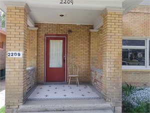 Doorway to property with brick siding and a patio