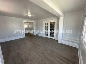 Empty room with a textured ceiling, french doors, and dark wood finished floors