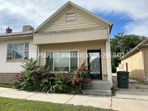 View of front of home with brick siding, a chimney, and covered porch