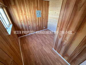 Unfurnished room featuring wood walls, wood finished floors, and a sauna