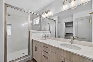 Bathroom featuring double vanity, a spacious closet, and a marble finish shower