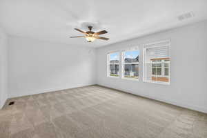 Empty room featuring light colored carpet and a ceiling fan