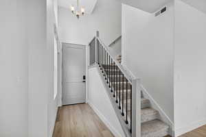 Staircase with wood finished floors, a chandelier, and a high ceiling