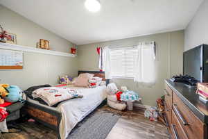 Bedroom featuring wood finished floors and lofted ceiling