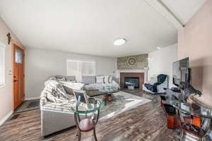 Living area with dark wood-style flooring, a textured ceiling, a large fireplace, and healthy amount of natural light