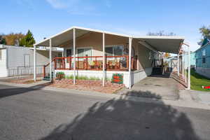 Manufactured / mobile home featuring an attached carport, a porch, and an outbuilding