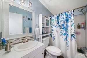 Full bathroom with vanity, a textured ceiling, shower / bath combination with curtain, and tasteful backsplash