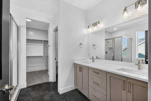 Full bathroom featuring a shower stall, a spacious closet, and double vanity
