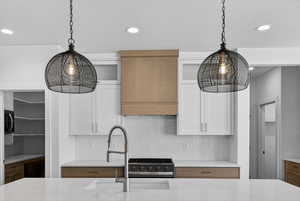Kitchen with white cabinetry, backsplash, extractor fan, recessed lighting, and pendant lighting