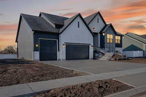 Modern farmhouse with concrete driveway, a shingled roof, board and batten siding, and an attached garage