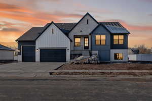 Modern inspired farmhouse featuring driveway, board and batten siding, brick siding, an attached garage, and a shingled roof