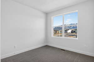 Unfurnished room with a mountain view and dark carpet