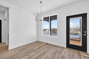 Unfurnished dining area featuring a chandelier and light wood-style flooring