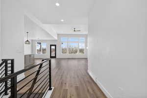 Corridor featuring light wood-style floors, recessed lighting, and an upstairs landing