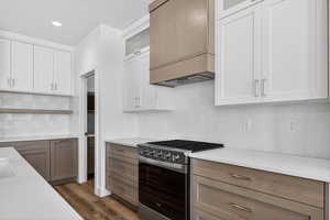 Kitchen featuring gas stove, decorative backsplash, white cabinetry, and recessed lighting