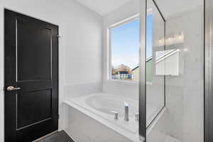 Bathroom with a marble finish shower and a garden tub