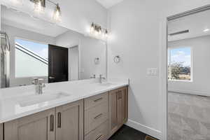 Bathroom with double vanity, plenty of natural light, a shower stall, and dark carpet