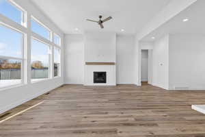 Unfurnished living room featuring light wood finished floors, a glass covered fireplace, ceiling fan, and recessed lighting