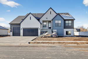 Modern farmhouse style home with concrete driveway, brick siding, board and batten siding, and a garage