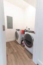 Laundry area with electric panel, wood finished floors, and separate washer and dryer