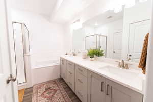 Full bath with a shower stall, double vanity, dark wood-type flooring, and a garden tub
