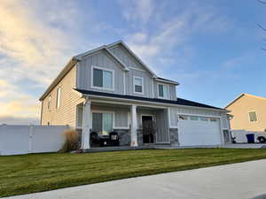View of front of property with board and batten siding, a porch, stone siding, a gate, and driveway