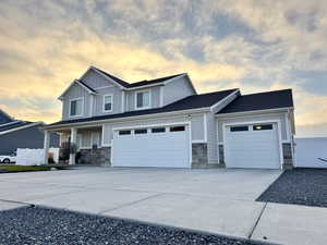 Craftsman inspired home with concrete driveway, stone siding, board and batten siding, roof with shingles, and a garage
