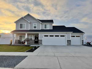 Craftsman-style house featuring stone siding, a porch, driveway, board and batten siding, and a garage