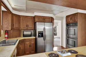 Kitchen with light countertops, stainless steel appliances, and brown cabinets