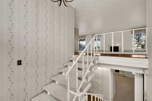 Staircase featuring plenty of natural light and wallpapered walls